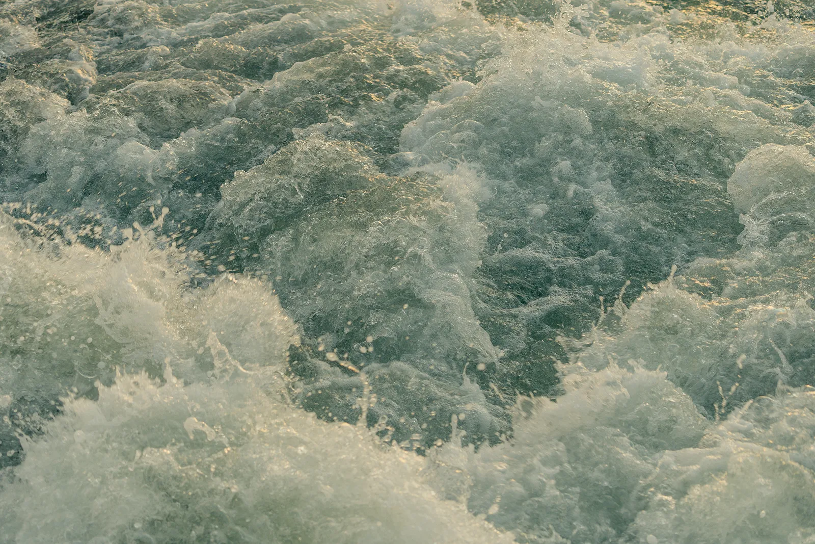 Close-up of turbulent, foaming water with waves splashing and bubbles.
