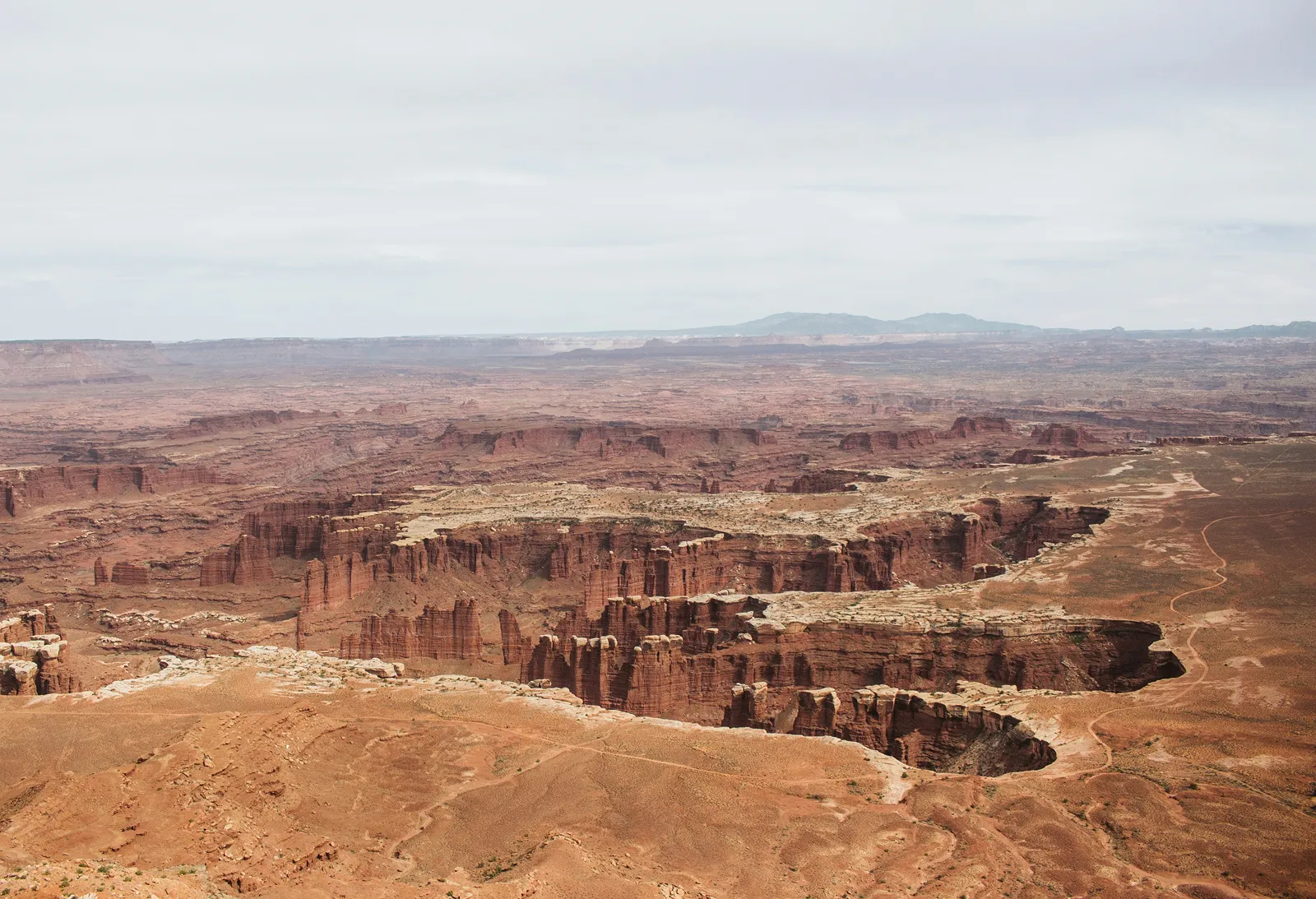Expansive view of a red rock canyon landscape under a cloudy sky.